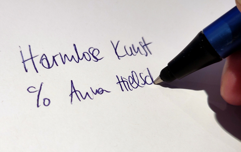 Foto von einem Stift, der "Harmlose Kunst c/o Anna Hielscher" schreibt. Anna Hielscher Harmlose Kunst